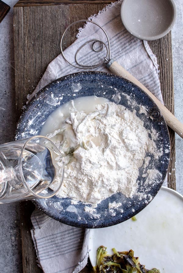 water pouring into flour mixture in blue bowl