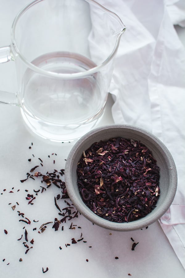 glass measuring cup with water, gray bowl with dried hibiscus flowers