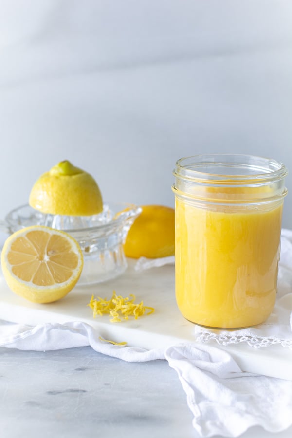 Jar of lemon curd on white cloth and sliced lemon