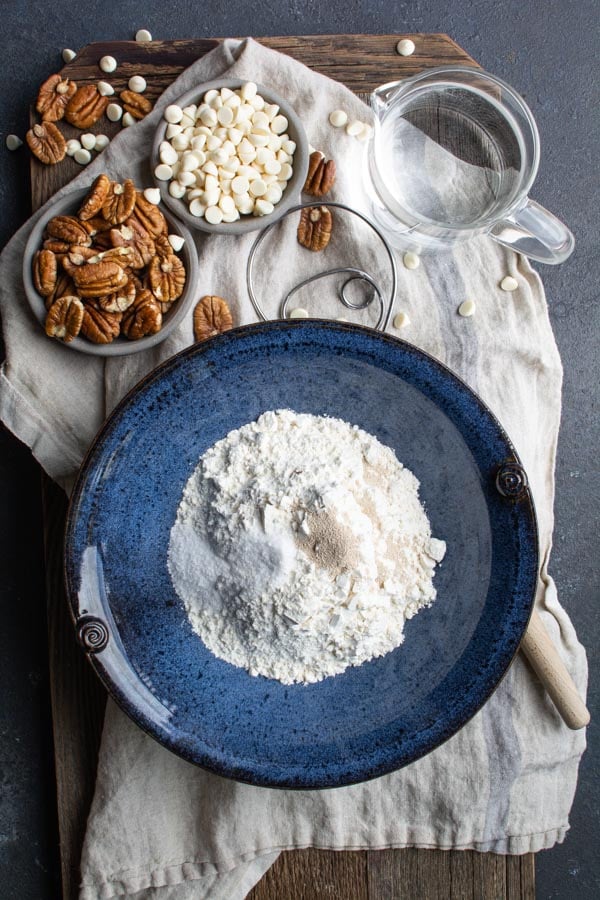 flour in blue bowl with pecans and white chocolate chips at the side