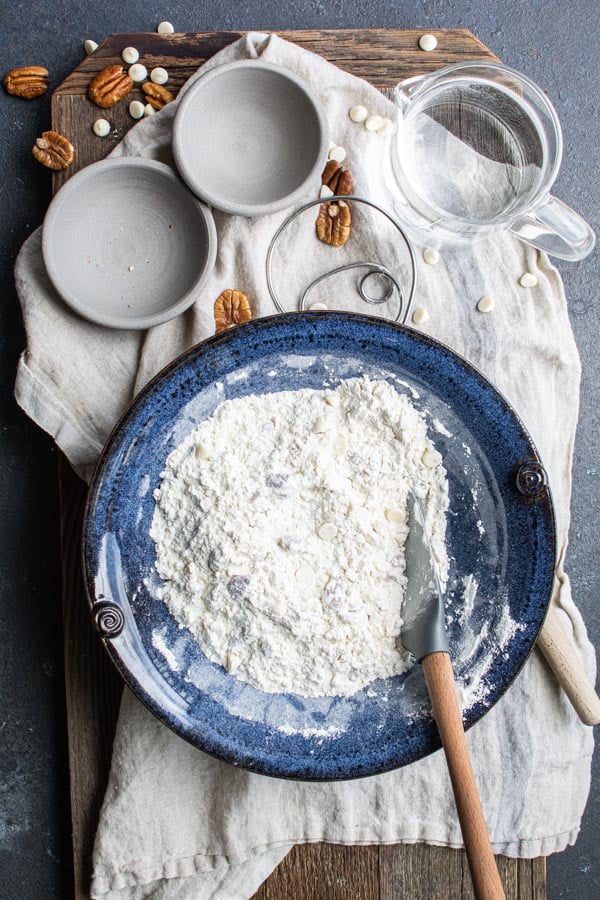 Blue bowl with mixed flour, pecans, white chocolate chips mixed