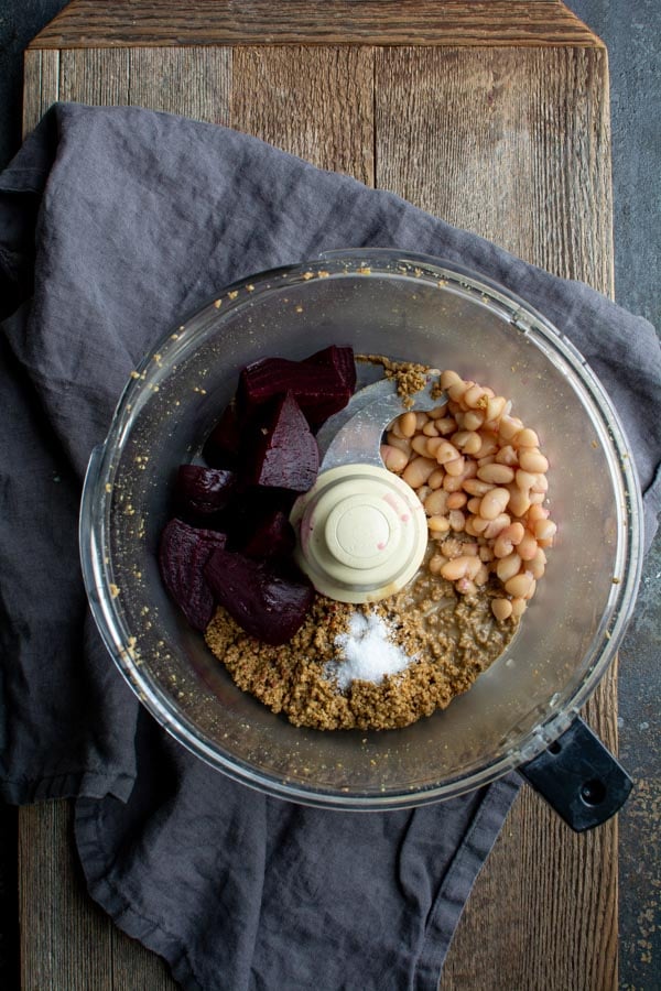 food processor bowl with ground pumpkin seeds, beets, and white beans