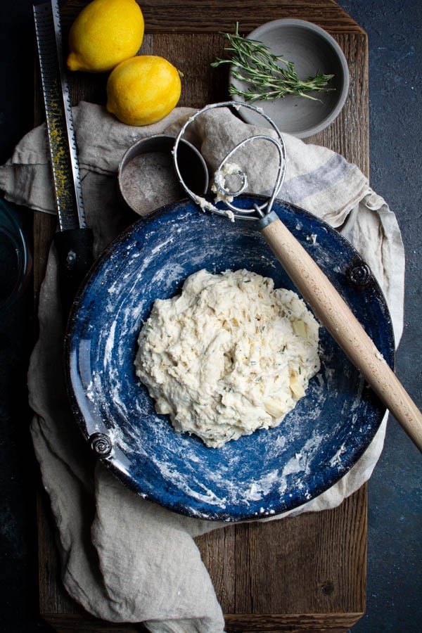 Blue bowl with hand kneader sitting on side with mixed bread dough in bowl