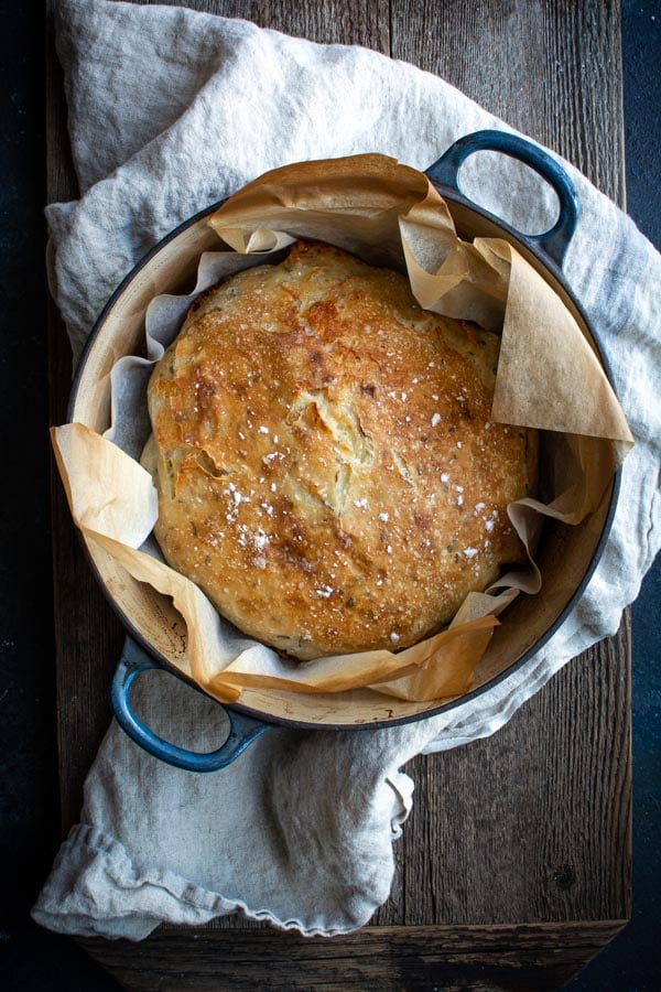 Overhead shot of No-knead Lemon Rosemary Gruyere Bread in pot and parchment paper