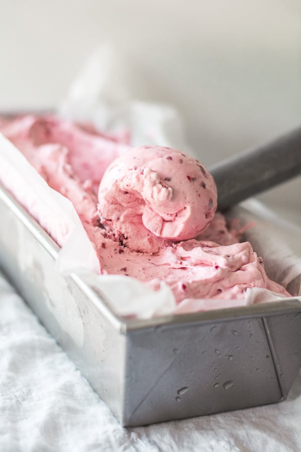 Quick and Easy Strawberry Ice Cream in a metal bread pan with an ice cream scoop