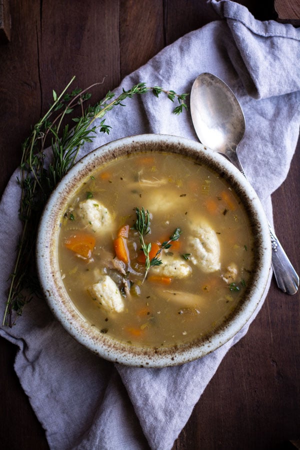 Overhead shot of chicken broth soup with herbs, vegetables and farina dumplings