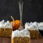 Three slices of pumpkin coconut cake on a cutting board with a fork stuck in the top of the center piece of cake