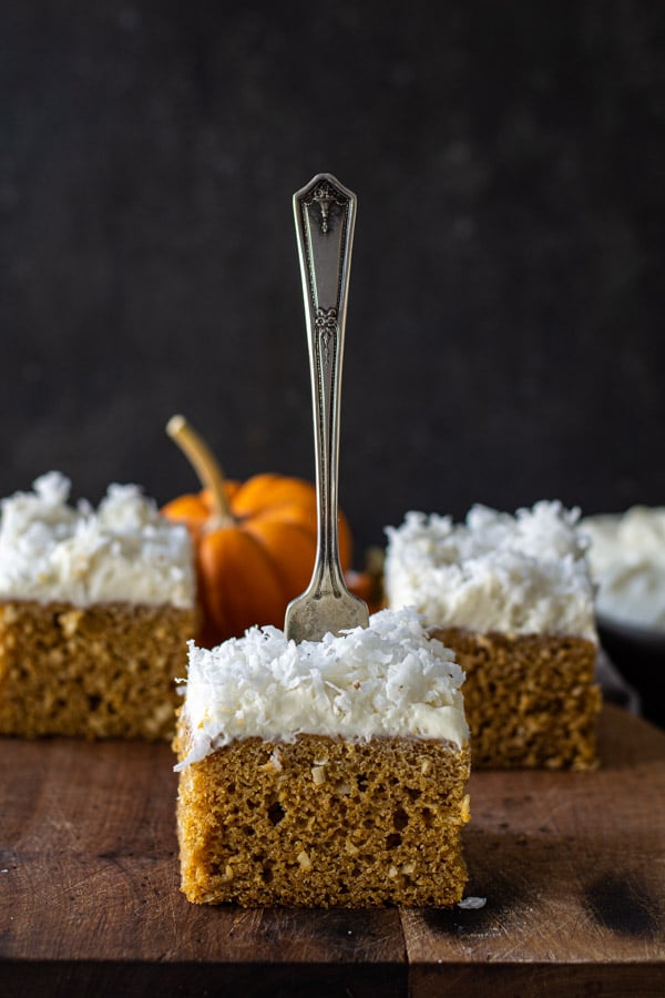 Three slices of pumpkin coconut cake on a cutting board with a fork stuck in the top of the center piece of cake