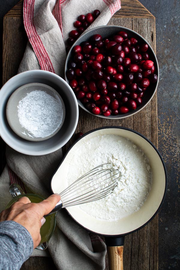 Sauce pan with flour and sugar whisked together, bowl of cranberries