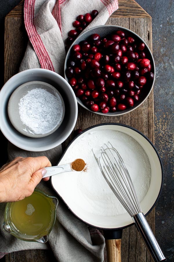 Saucepan with sugar and cinnamon, bowl of cranberries