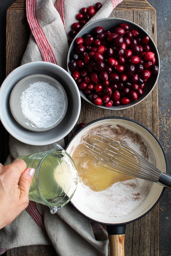 saucepan with peach juice added to sugar mixture, bowl of cranberries