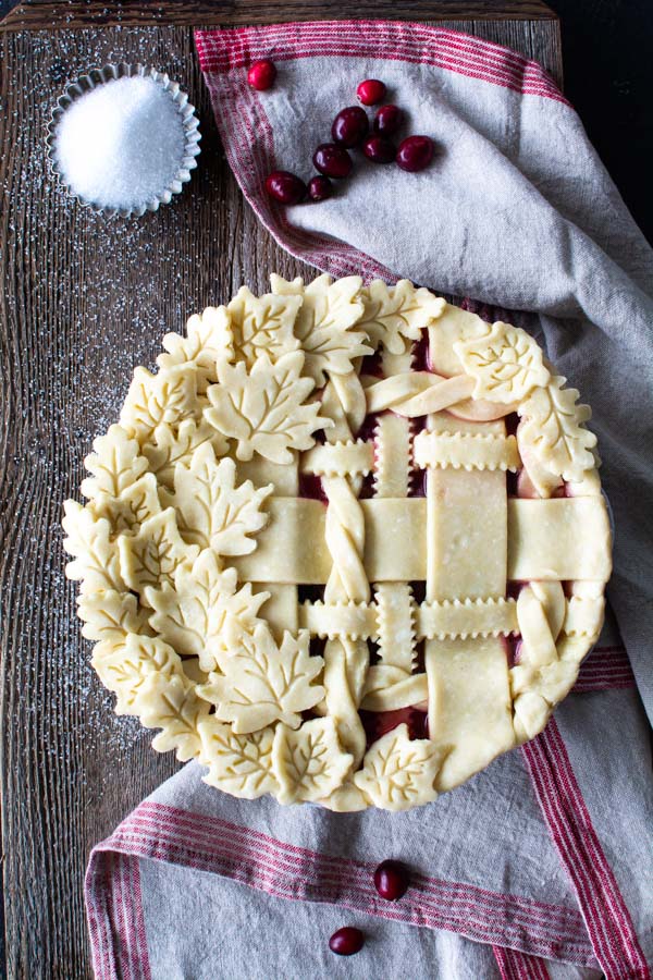 Decorative lattice on cranberry peach pie, sanding sugar, and cranberries