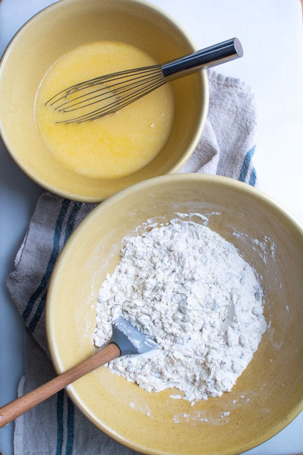 Large bowl with flour covered dried fruit. Smaller bowl with egg butter mixture