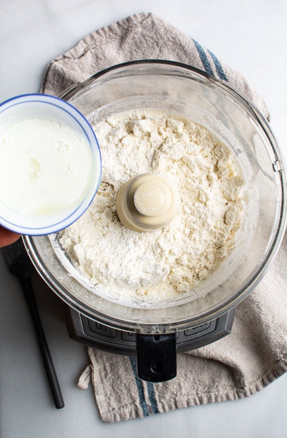 Food processor bowl with almonds flour and egg whites in small bowl.