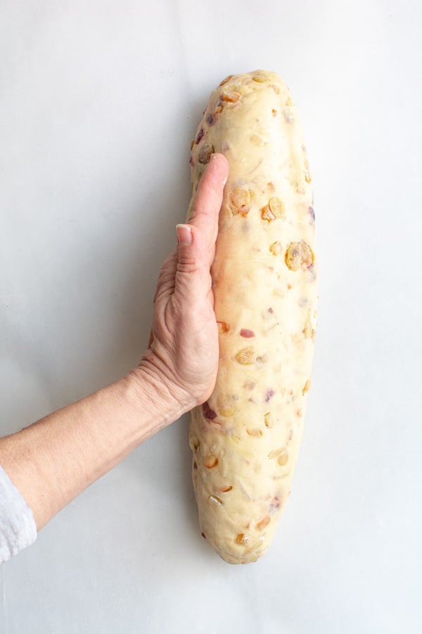 A hand pressing dough around marzipan