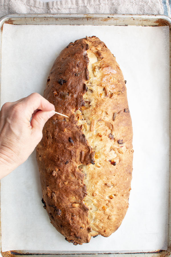 Baked Stollen loaf with hand poking holes on the top of the bread.