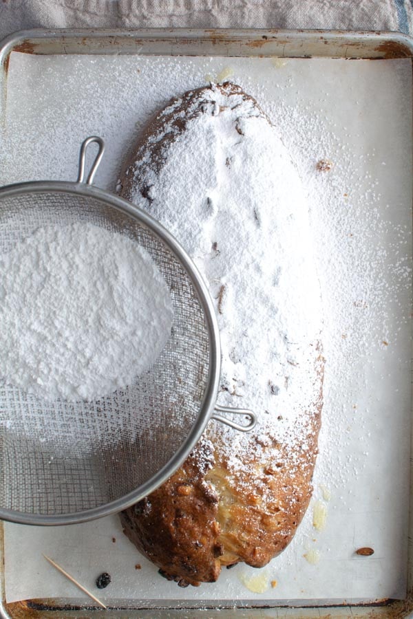 Large sieve sifting powder sugar over baked Stollen