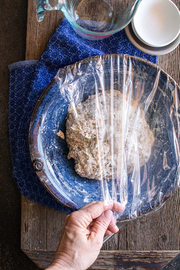 Mixed Dakota bread in a bowl with plastic wrap over it