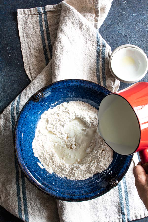 Small pan with warm milk pouring on top of paratha ingredients