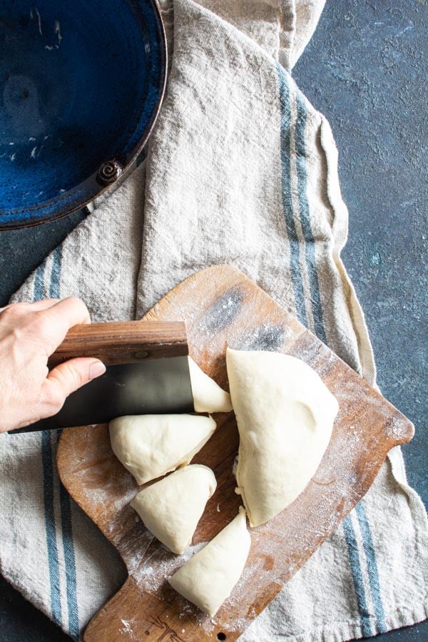 Paratha dough cut into segments on a floured cutting board