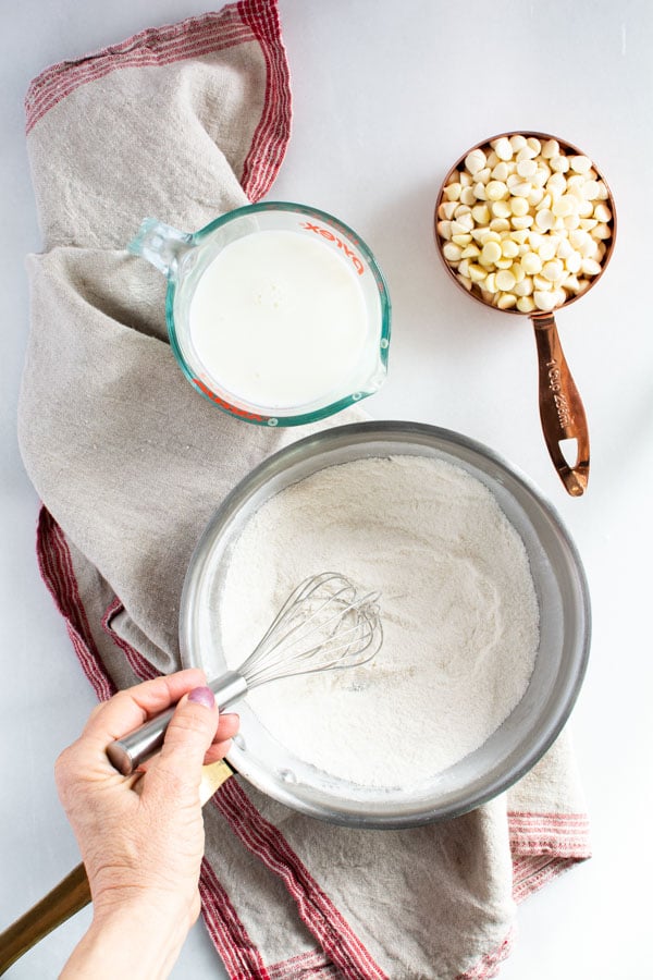 saucepan with whisk stirring flour and sugar