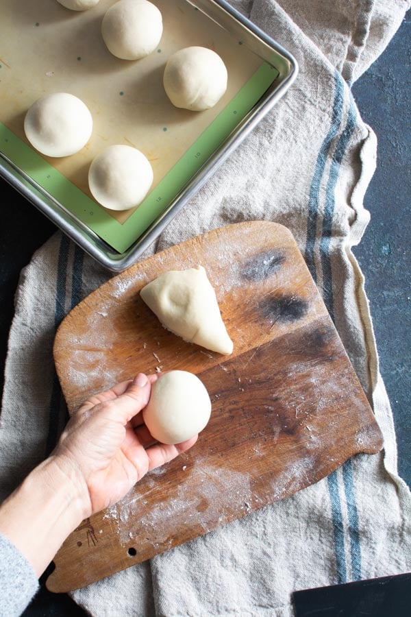 Segments of paratha dough rolled into balls placed on baking sheet