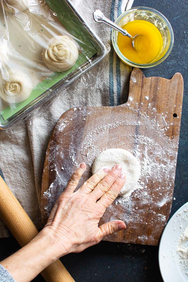 Flattened round of paratha dough on a floured board.