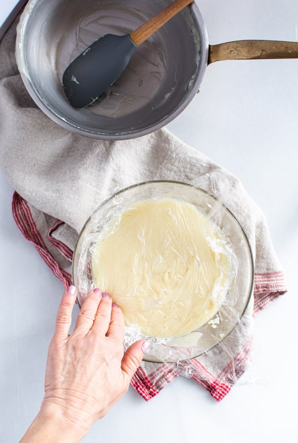 Glass bowl with white chocolate roux and plastic wrap pressed on top