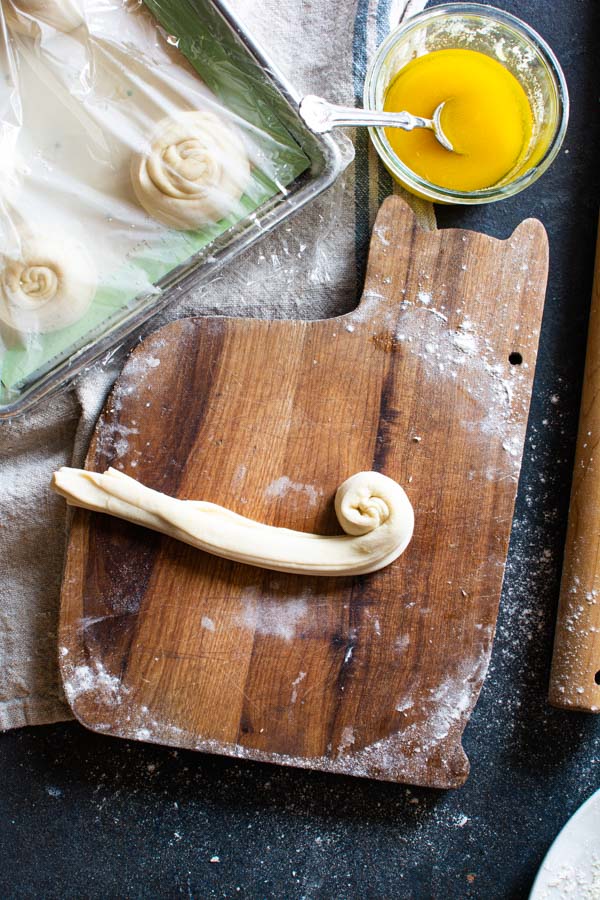 Paratha strip being rolled into a round shape like a cinnamon roll