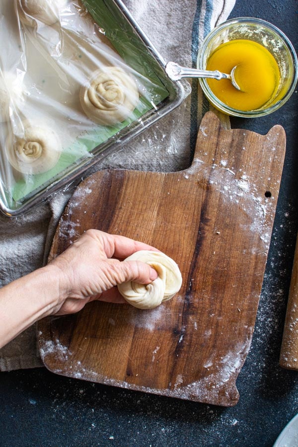 Flatten round paratha disk with tail end of dough pressed into the back of the disk