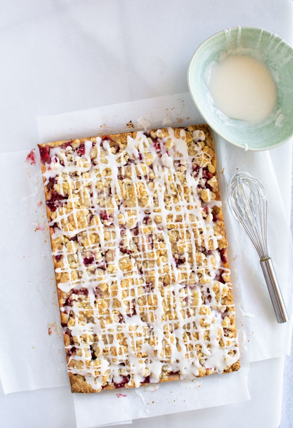 Uncut Strawberry Rhubarb Almond Crumble Bars drizzled with glaze.