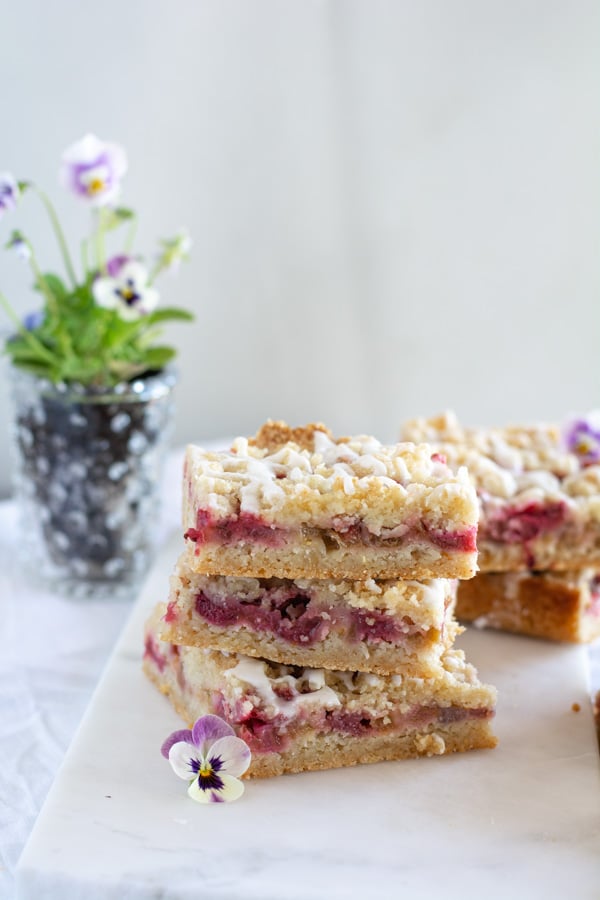 Stacked Strawberry Rhubarb Almond Crumble Bars on a white cloth