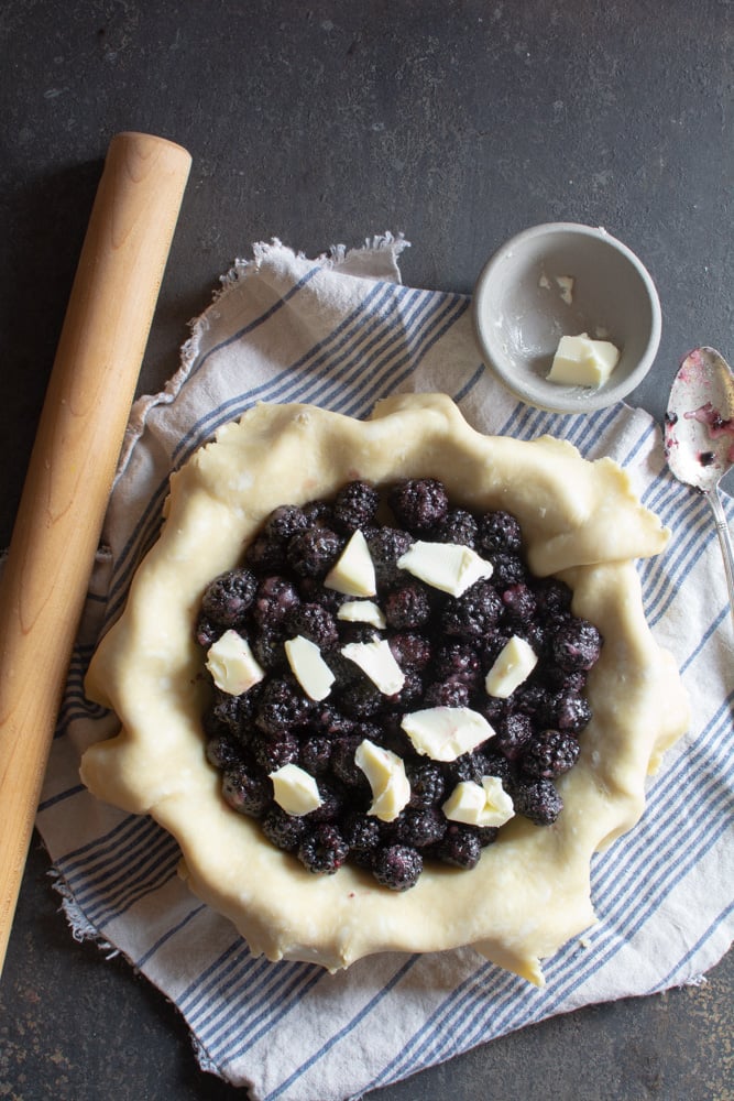 Pie dough filled with blackberries dotted with butter