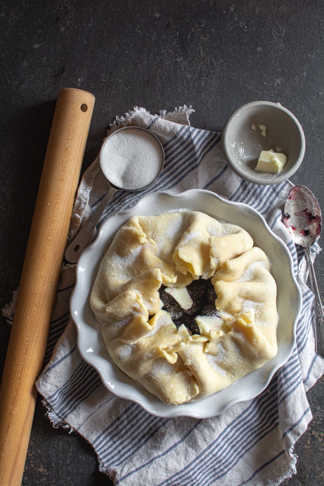 blackberry cobbler before baking sprinkled with sugar and dotted with butter