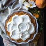 Fresh peach pie topped with whipped cream.