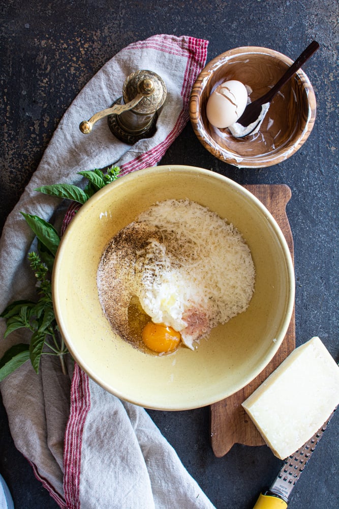 Yellow bowl with ricotta, parmesan, eggs, salt and pepper