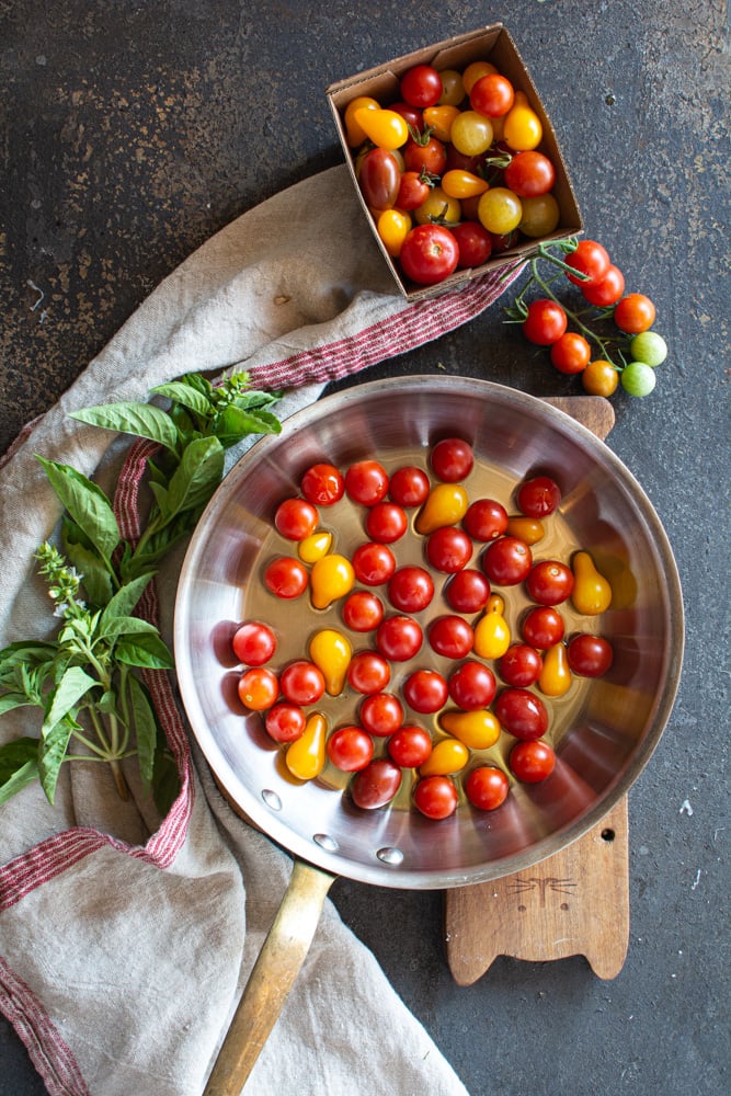 Skillet with olive oil, and red cherry tomatoes and yellow pear tomatoes