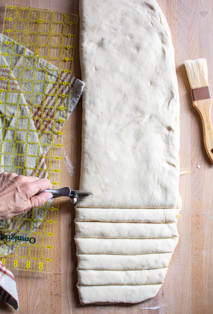 Pizza cutter cutting 1-inch strips of dough.