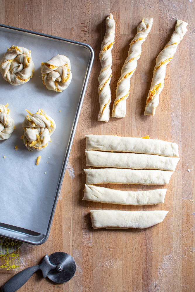 Twisting dough and shaping into a knot for cheddar rolls