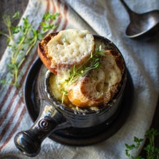 overhead shot of french onion soup with thyme sprigs on top of gruyere toast