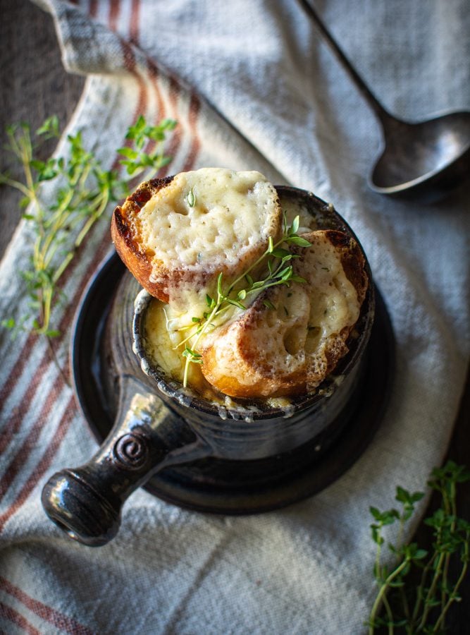 overhead shot of french onion soup with thyme sprigs on top of gruyere toast