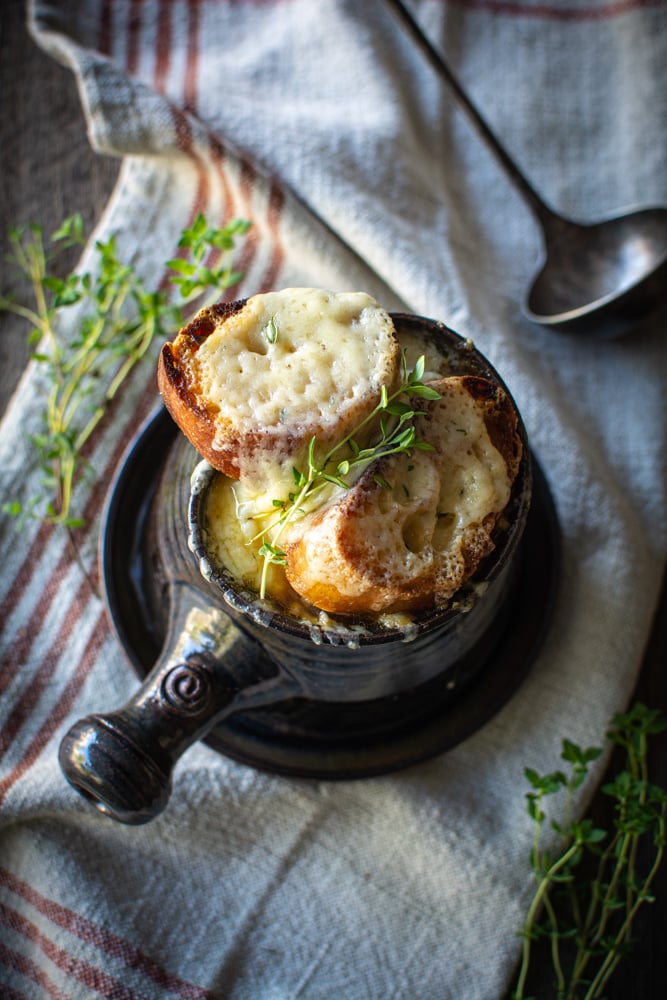 overhead shot of french onion soup with thyme sprigs on top of gruyere toast