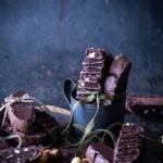 Black mug with chocolate hazelnut biscotti stacked inside with green bow tied around biscotti