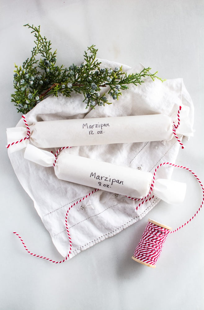 rolls of marzipan in white paper tied with red striped twine