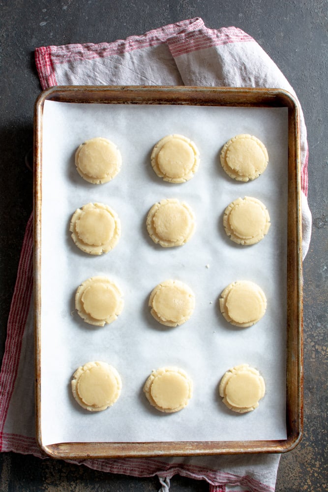 A dozen marzipan cookies before baking on a baking sheet