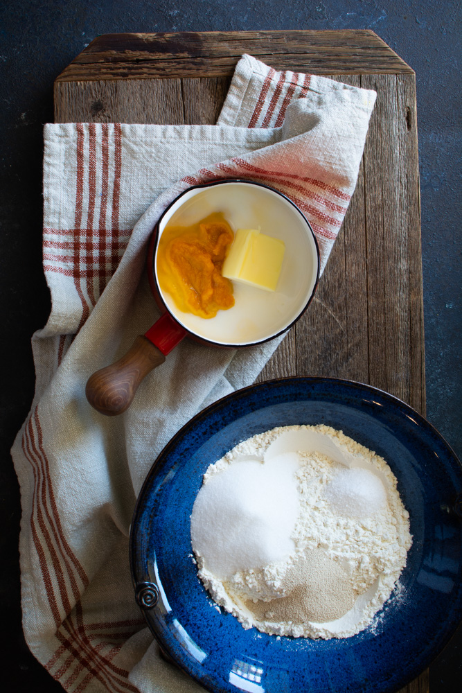 Large bowl with bun ingredients and pan with pumpkin, milk, and butter