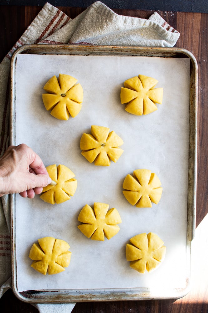 Unbaked Pumpkin shaped buns on a baking sheet.