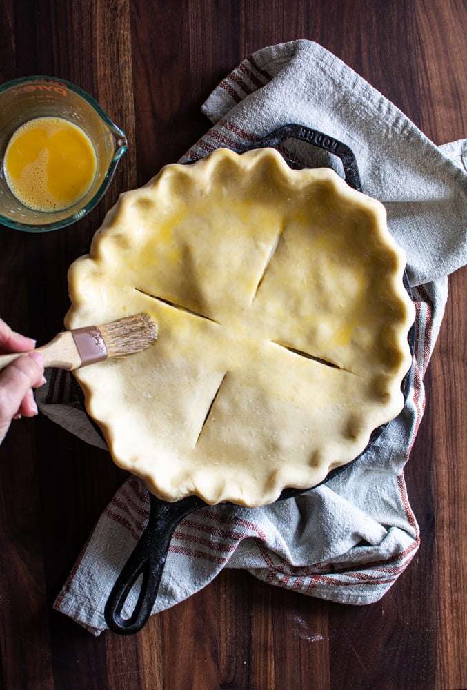 Roasted Chicken Pot Pie topped with puff pastry being brushed with egg wash.