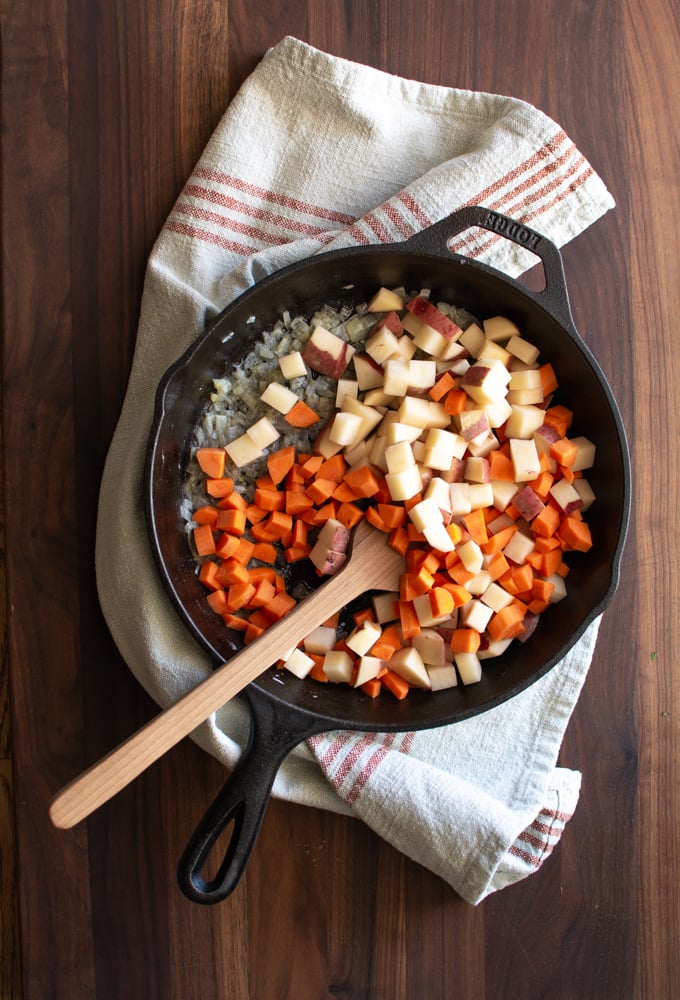 Skillet with chopped onions, potatoes, and carrots sauteed in skilletns, pot