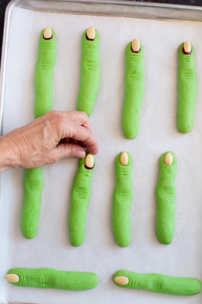 Finger placing an almond at the tip of the cookie finger.